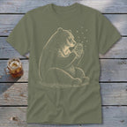 Bear holding a jar with stars and fireflies on a green t-shirt.