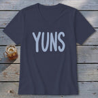 Navy v-neck t-shirt with light blue "YUNS" graphic, next to a drink.
