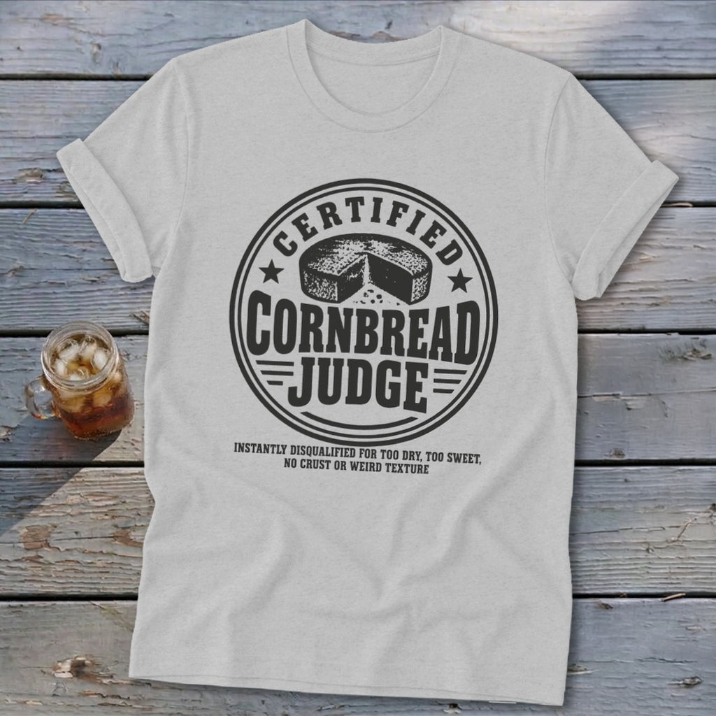 A light gray crewneck t-shirt featuring a circular graphic with text reading "Certified Cornbread Judge".