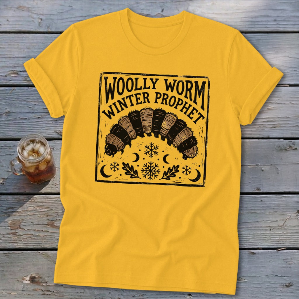 Yellow crewneck t-shirt featuring a black block-print graphic of a woolly worm with snowflakes, leaves, and text reading Woolly Worm Winter Prophet.
