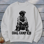 White sweatshirt with black graphic of a boy in overalls and cap holding a bucket, text "COAL CAMP KID".