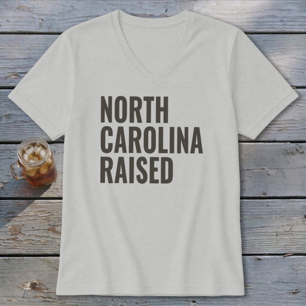 Light grey v-neck t-shirt with "NORTH CAROLINA RAISED" printed in dark grey text.