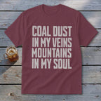 A maroon t-shirt with white distressed text that reads COAL DUST IN MY VEINS MOUNTAINS IN MY SOUL.