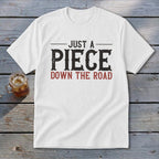 White t-shirt with "JUST A PIECE DOWN THE ROAD" text in distressed black and red font.
