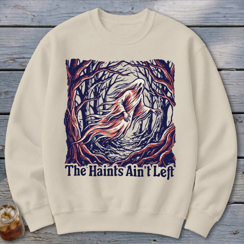 Cream sweatshirt with graphic of a ghost in a forest, reads "The Haints Ain't Left".