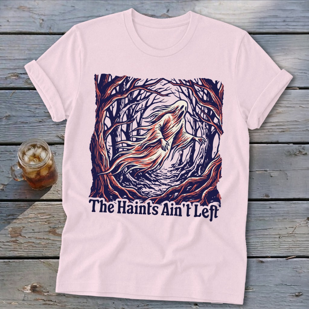 Pink t-shirt with a ghost in a forest graphic and text "The Haints Ain't Left".