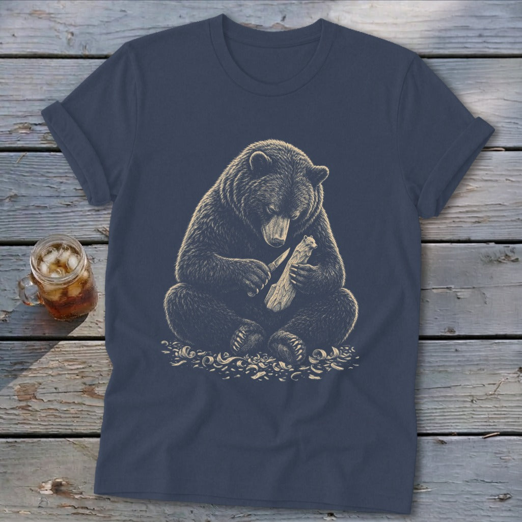 T-shirt graphic of a bear carving wood with a knife.