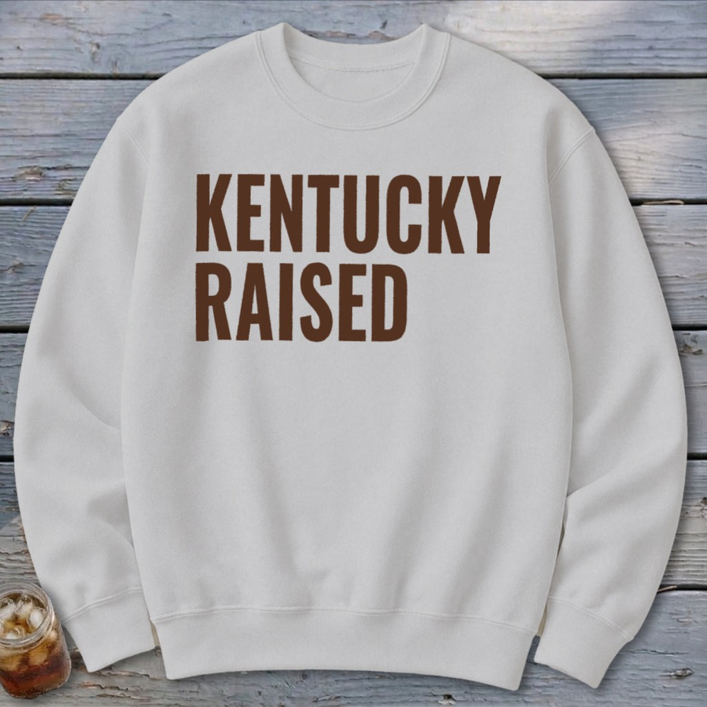 White crewneck sweatshirt with "KENTUCKY RAISED" text in brown.