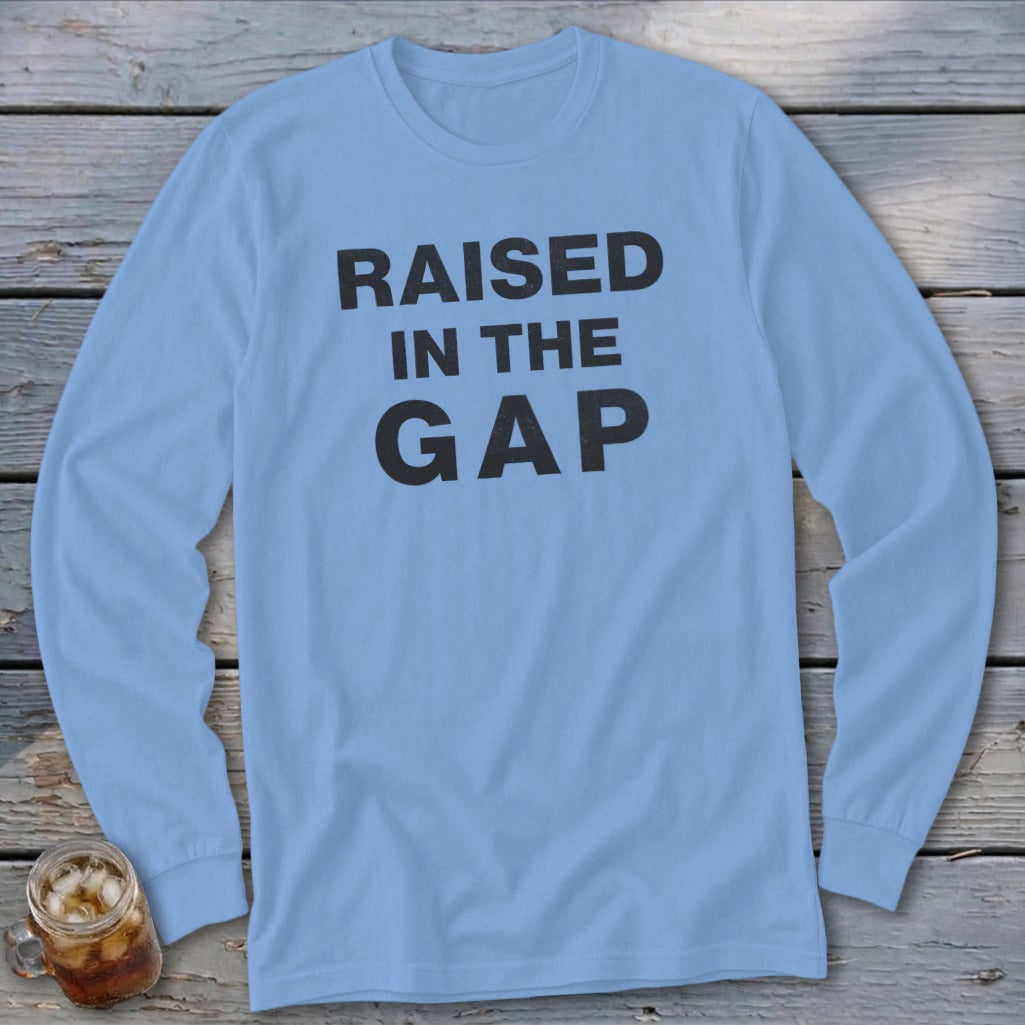 Light blue long sleeve shirt with black text "RAISED IN THE GAP".