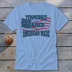 Light blue t-shirt with distressed American flag design and text: Tennessee Raised American Made.