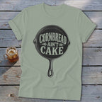 Light green t-shirt with "Cornbread Ain't Cake" inside a skillet graphic.
