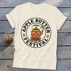 Cream t-shirt with circular Apple Butter Festival graphic featuring a kettle over a fire.