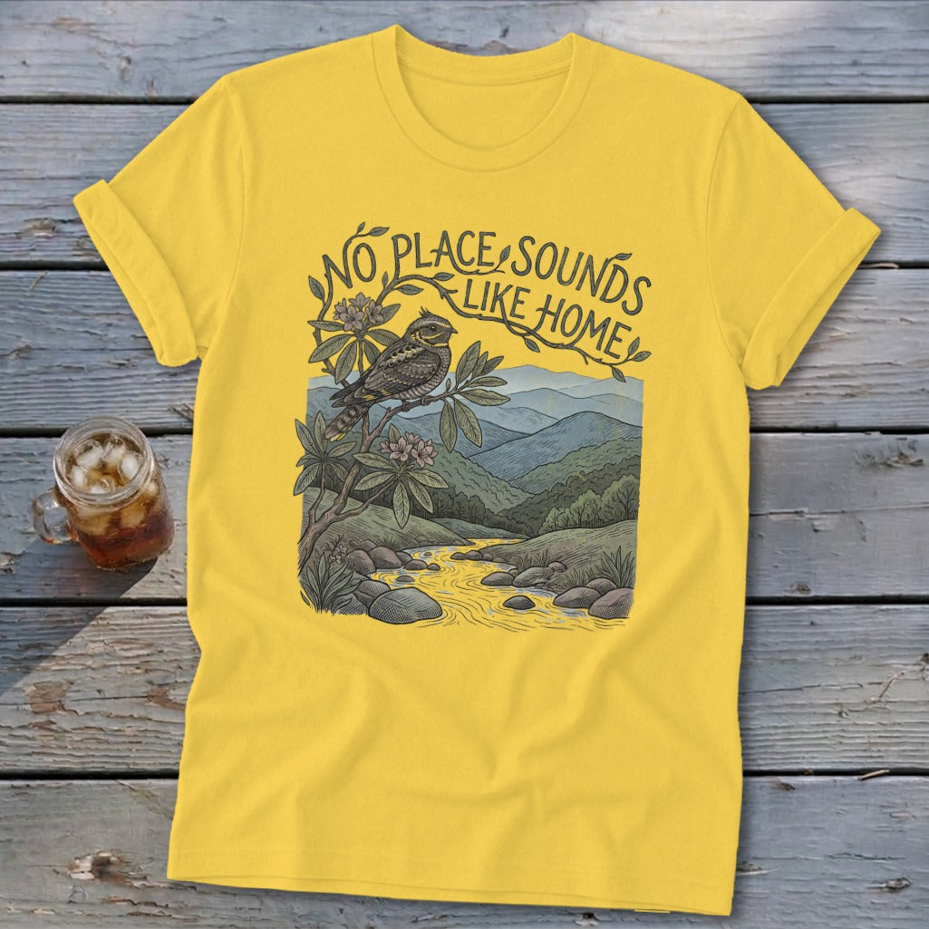 Yellow t-shirt with "No place sounds like home" text, bird, and mountain landscape graphic.