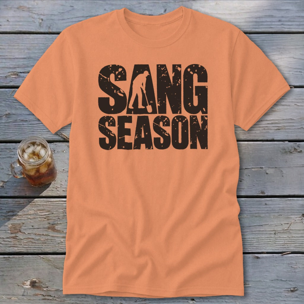 An orange t-shirt featuring distressed black text that reads SANG SEASON with a silhouette of a person digging.