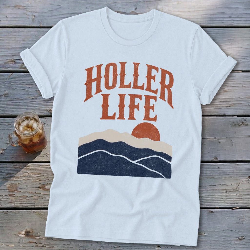 A white t-shirt with the text HOLLER LIFE and a sunset mountain graphic.