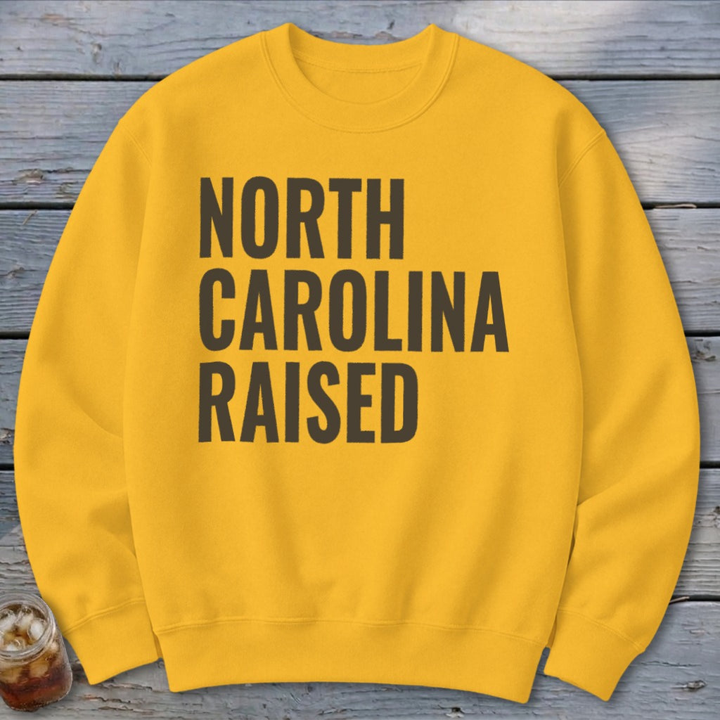 Yellow sweatshirt with "NORTH CAROLINA RAISED" text in dark gray.