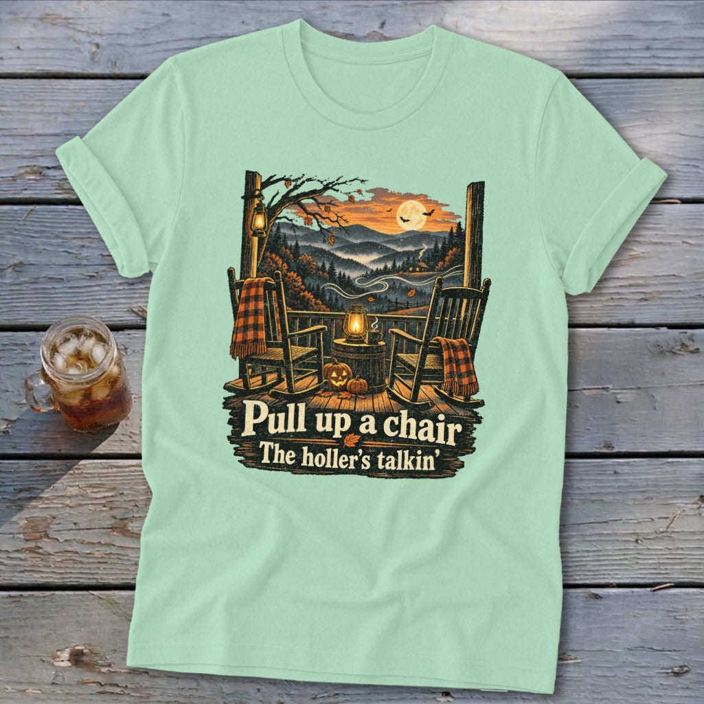 Light green t-shirt with porch scene, rocking chairs, pumpkins, and text "Pull up a chair The holler's talkin'".