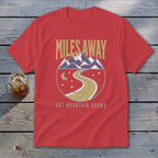 Red t-shirt with "Miles Away But Mountain Bound" text and mountain graphic.