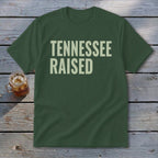 Green t-shirt with "TENNESSEE RAISED" text in light beige.