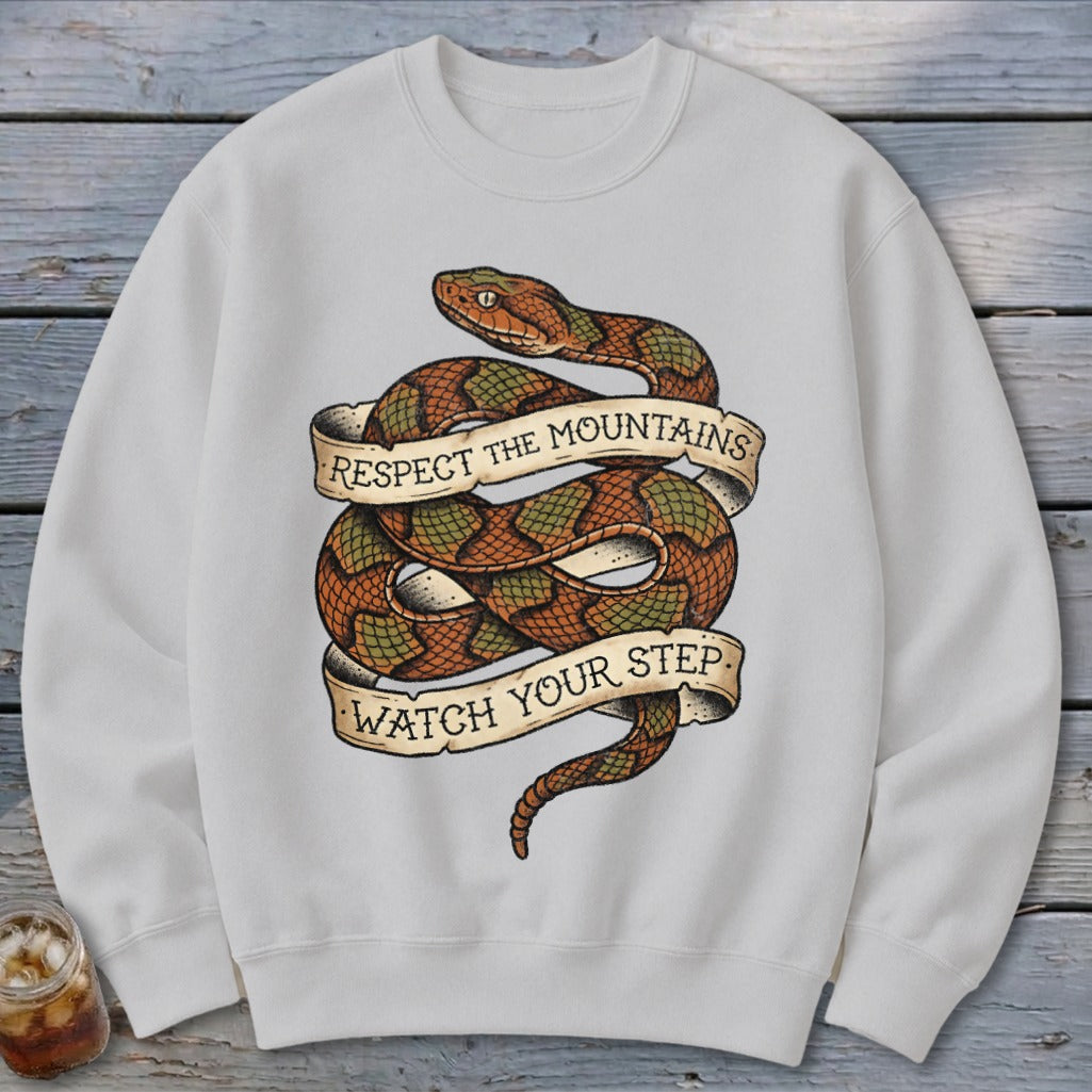 White sweatshirt with a coiled snake graphic and text reading "Respect the Mountains Watch Your Step."