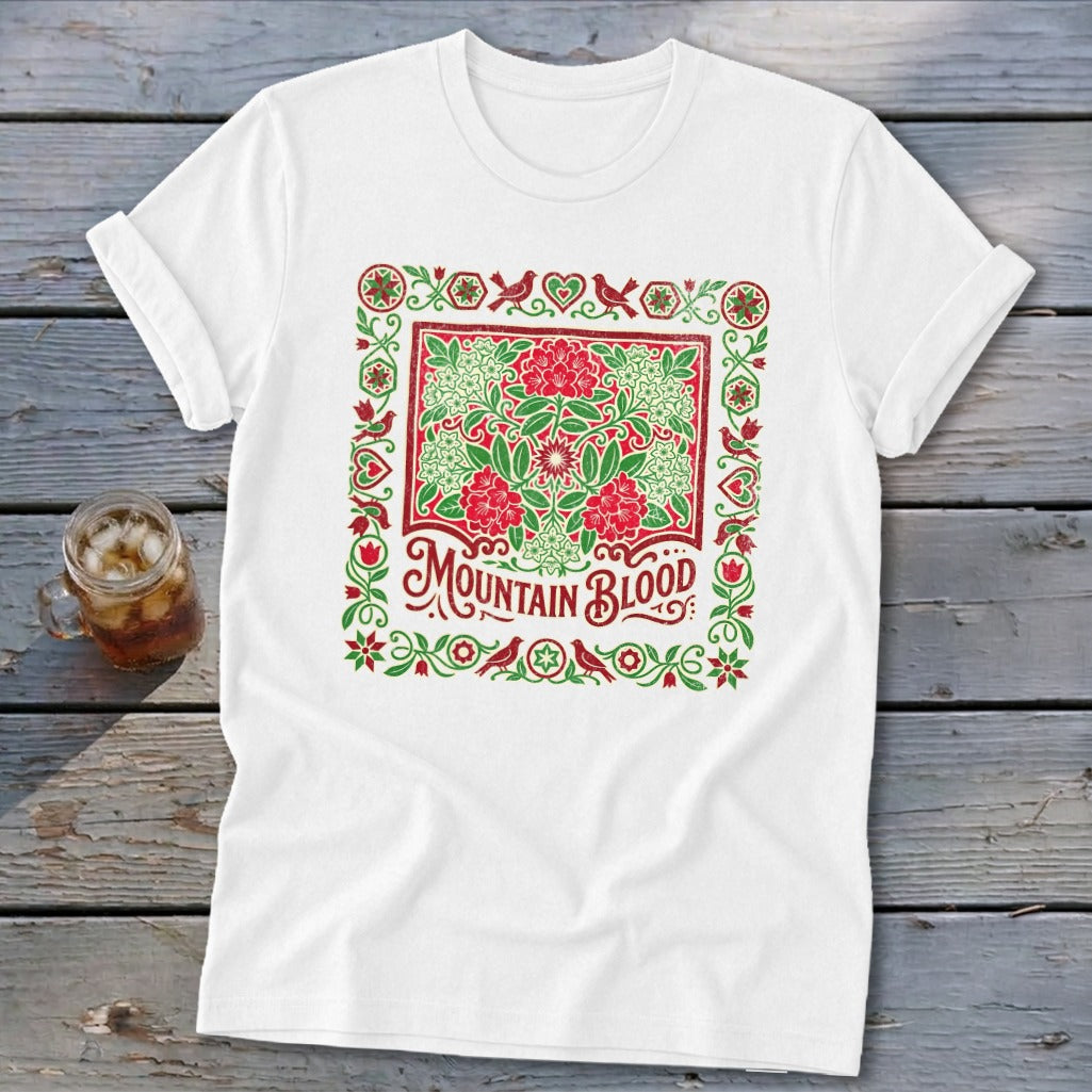 White t-shirt with a red and green floral design and "Mountain Blood" text.