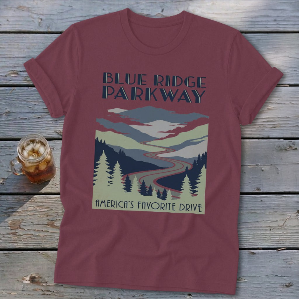 Maroon t-shirt with a vintage Blue Ridge Parkway landscape graphic and text on a wooden surface.