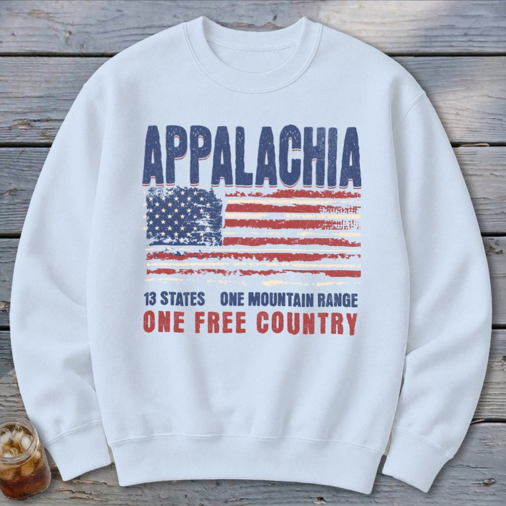 A white crewneck sweatshirt featuring a distressed graphic with the text Appalachia, a weathered American flag, and the slogan 13 states one mountain range one free country.