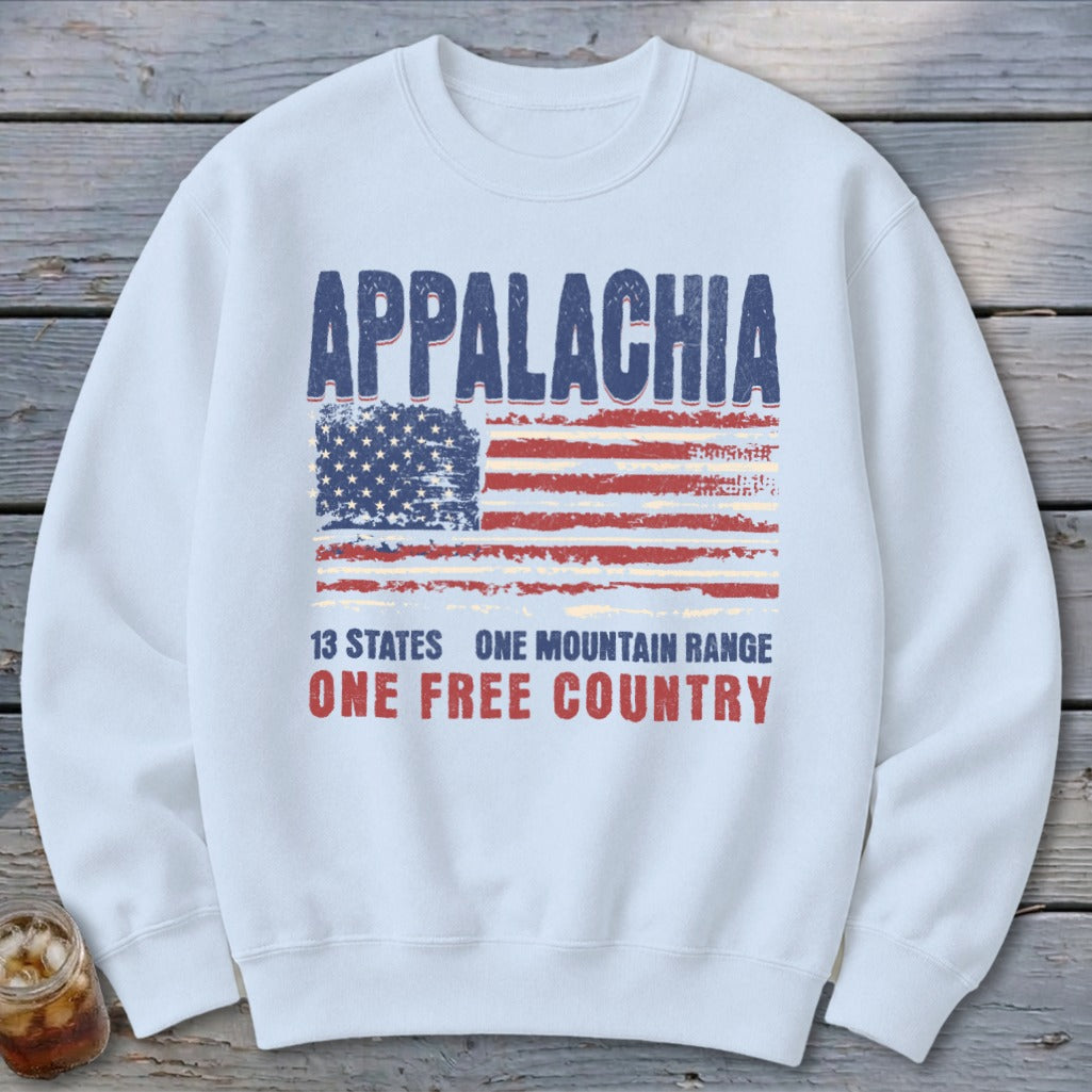 A white crewneck sweatshirt featuring a distressed graphic with the text Appalachia, a weathered American flag, and the slogan 13 states one mountain range one free country.