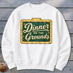 White crewneck sweatshirt featuring a distressed green marquee sign graphic with the text "Dinner on the Grounds".