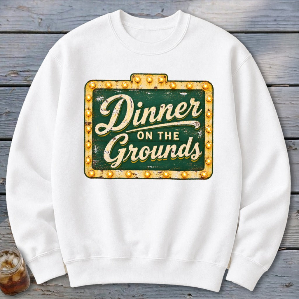 White crewneck sweatshirt featuring a distressed green marquee sign graphic with the text "Dinner on the Grounds".
