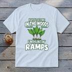 Light blue t-shirt featuring green graphic text and ramp illustrations on a wooden background.