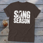 Brown short-sleeve t-shirt with white distressed text reading "SANG SEASON" and a silhouette of a digger.
