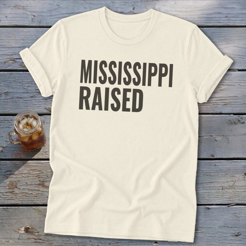 Cream t-shirt with "MISSISSIPPI RAISED" text, beside a drink.