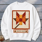 White sweatshirt with a quilted maple leaf design and "MAPLE LEAF" text.