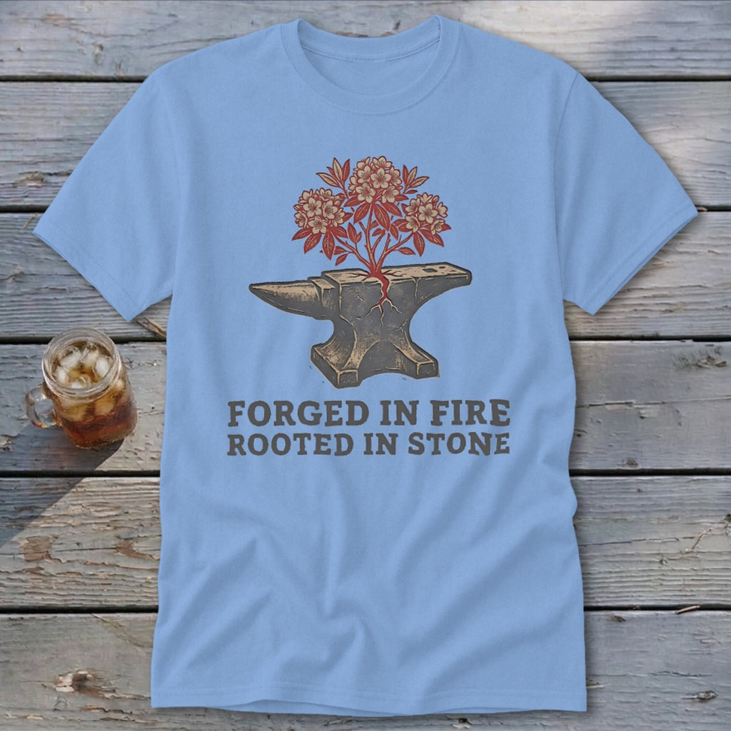 Light blue t-shirt with an anvil with a plant growing from it and text "FORGED IN FIRE ROOTED IN STONE".