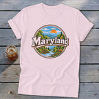 Pink t-shirt with a circular Maryland landscape graphic featuring mountains, trees, river, and a deer.