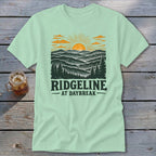 Light green t-shirt with a mountain and sunrise graphic and text "RIDGELINE AT DAYBREAK".