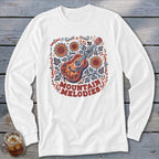 White long-sleeve t-shirt featuring a folk art illustration of an acoustic guitar, sunflowers, leaves, and text reading Mountain Melodies.