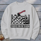 White sweatshirt with a black and red graphic of an axe in stacked firewood, text reads "STACKED FOR THE SEASON".