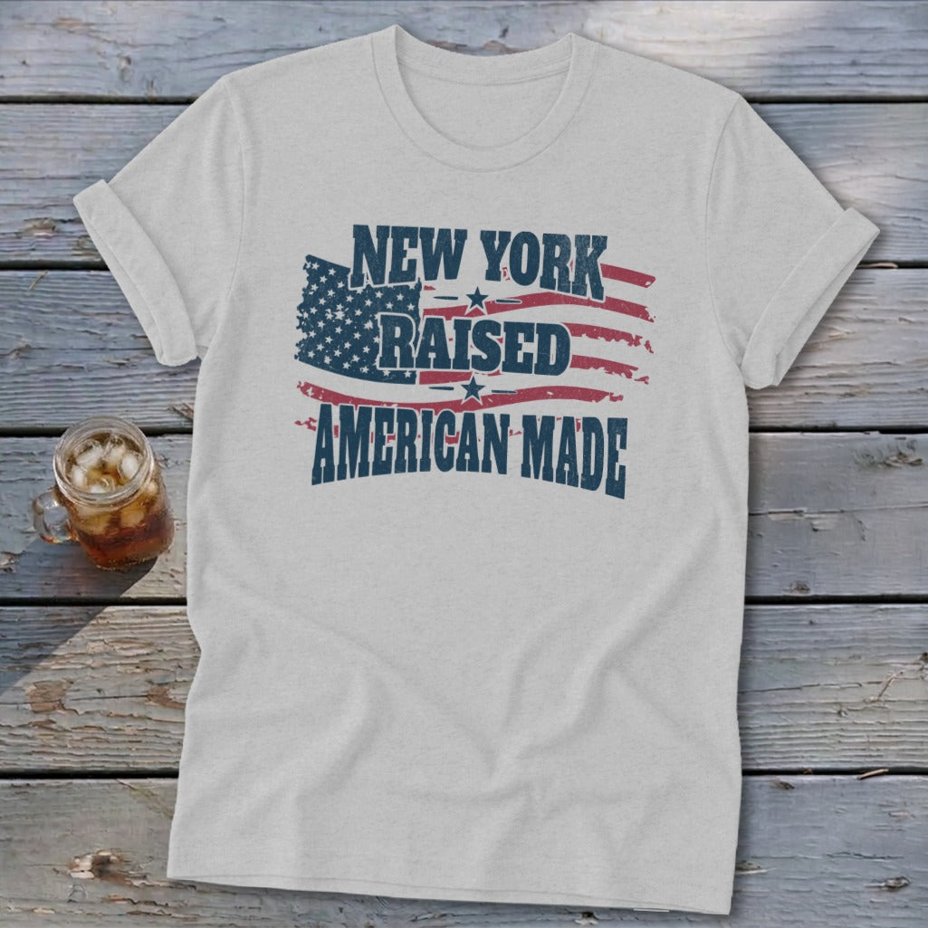 Light gray t-shirt with a distressed graphic reading New York Raised American Made over a stylized US flag.