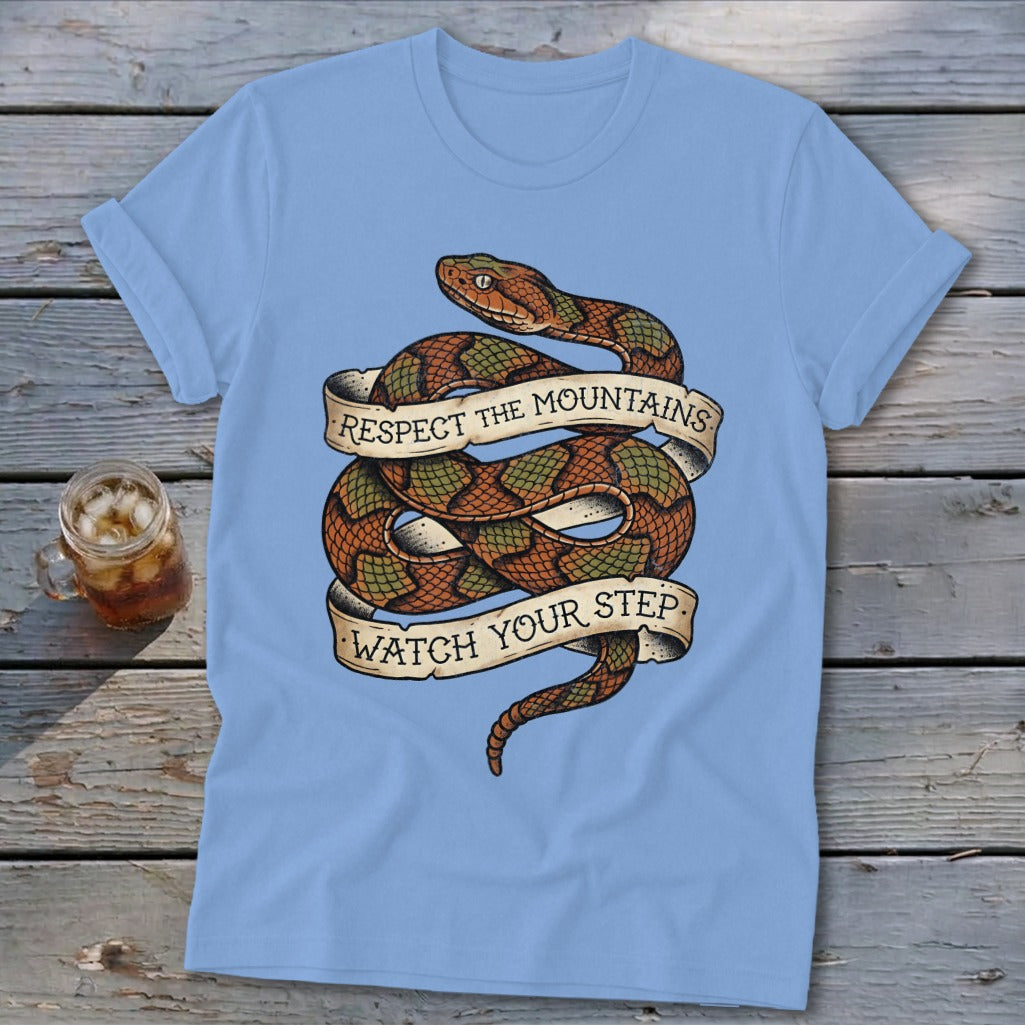 Light blue t-shirt with a coiled snake and banner text "RESPECT THE MOUNTAINS WATCH YOUR STEP".