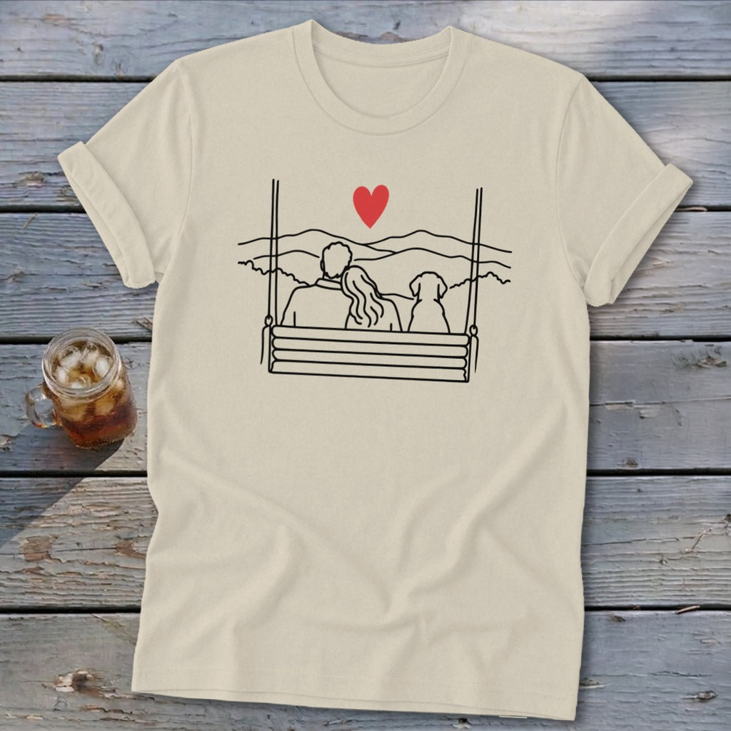 Cream t-shirt with line drawing of couple and dog on a swing with mountains and red heart.