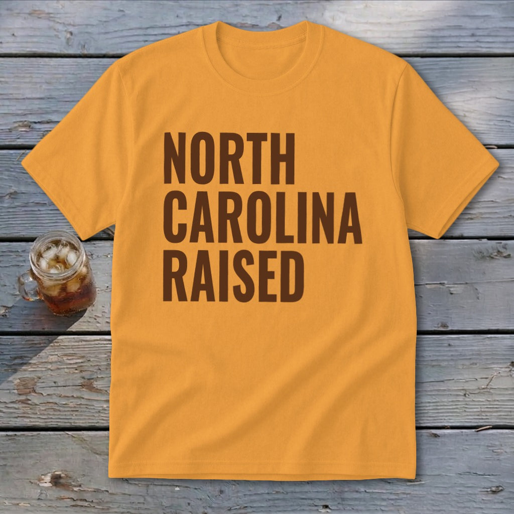 Orange t-shirt with brown text reading "NORTH CAROLINA RAISED".