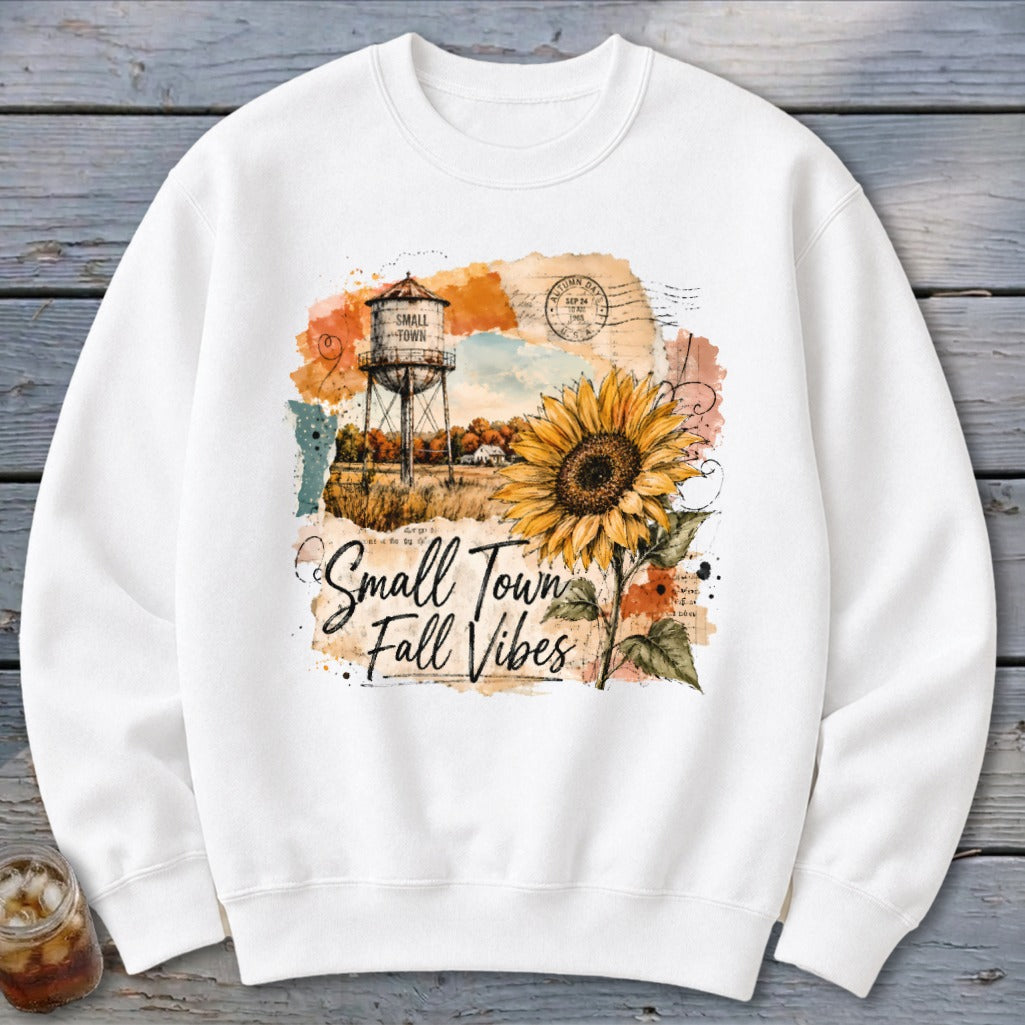 White sweatshirt with sunflower, water tower, and "Small Town Fall Vibes" text.