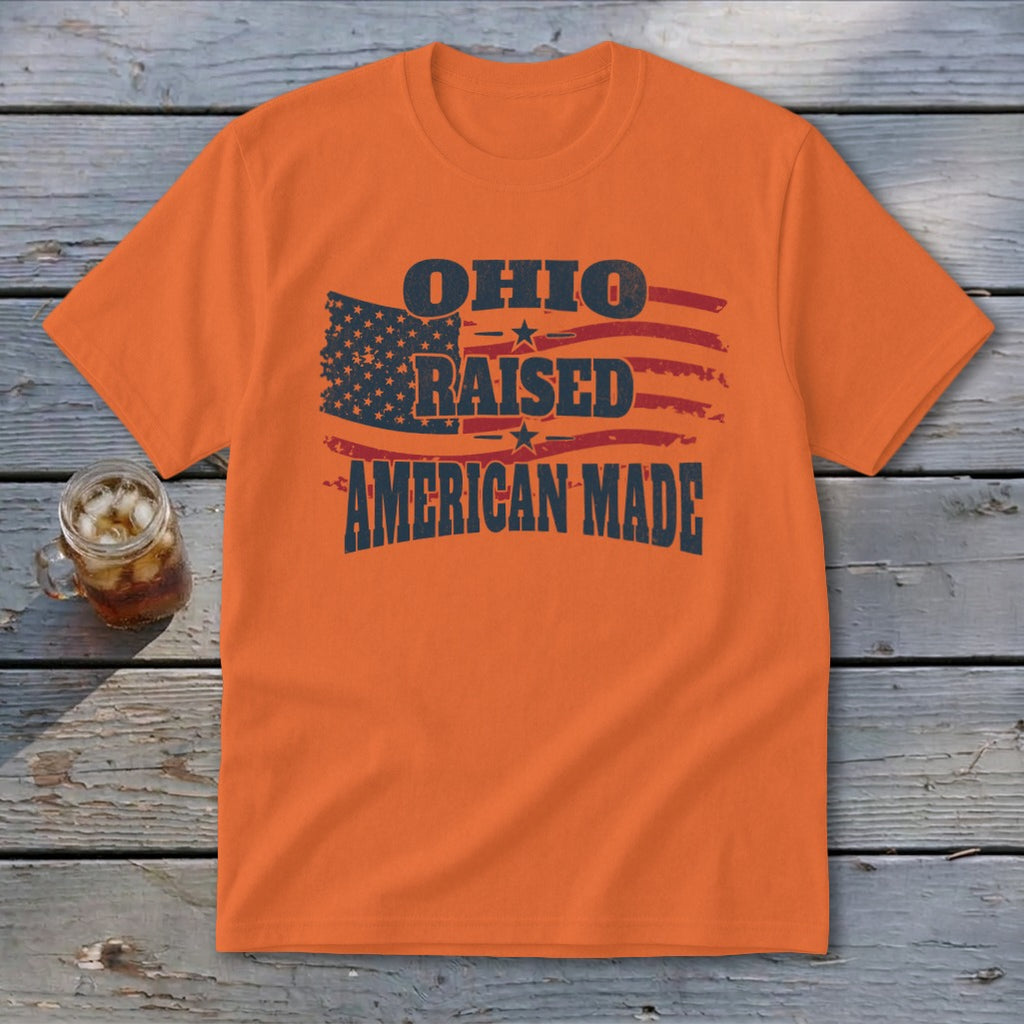 An orange t-shirt featuring a graphic with an American flag and the text Ohio Raised American Made.