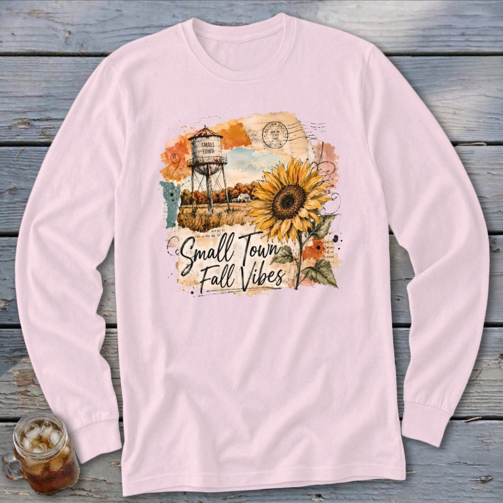 Pink long sleeve shirt with "Small Town Fall Vibes" graphic featuring a sunflower and water tower.