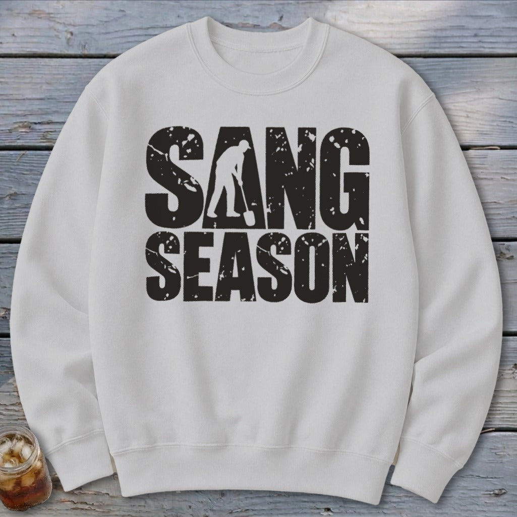 A white crewneck sweatshirt featuring a distressed black graphic that reads SANG SEASON with a digger silhouette.