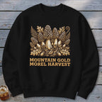Black sweatshirt with a graphic of morel mushrooms, leaves, and acorns; text reads "MOUNTAIN GOLD MOREL HARVEST."