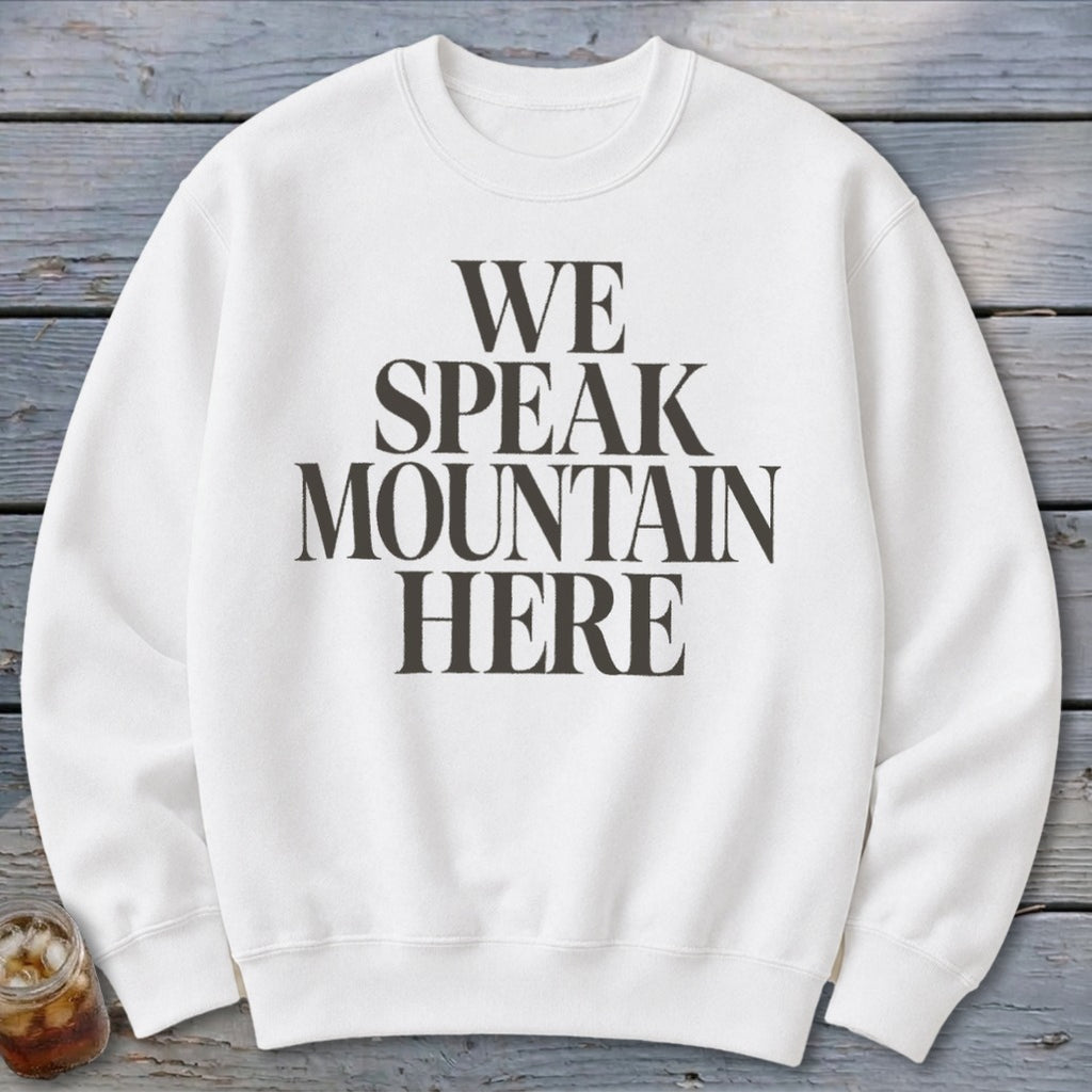 White crewneck sweatshirt with "WE SPEAK MOUNTAIN HERE" printed on the front.