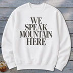 White crewneck sweatshirt with "WE SPEAK MOUNTAIN HERE" printed on the front.